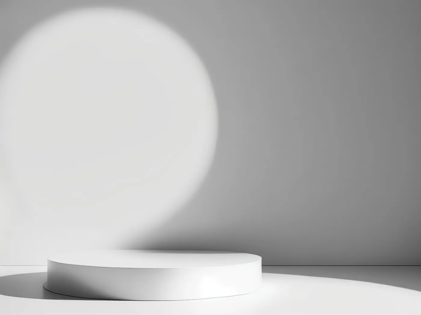 A single white plinth standing alone in a pale grey room, lit by one soft circle of light.
