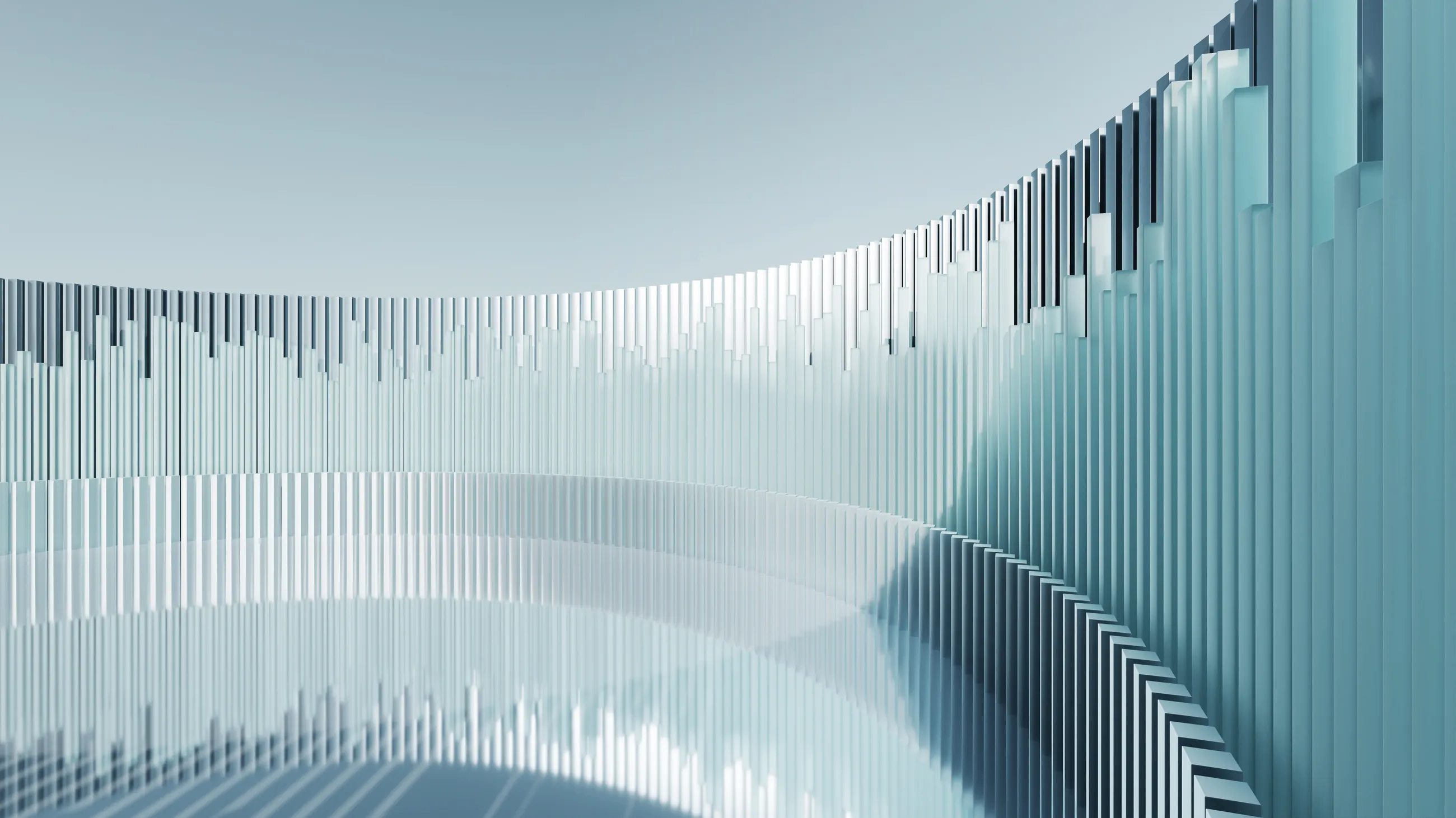 A curved wall of pale blue-green vertical slats of varying heights, sweeping around an empty floor.