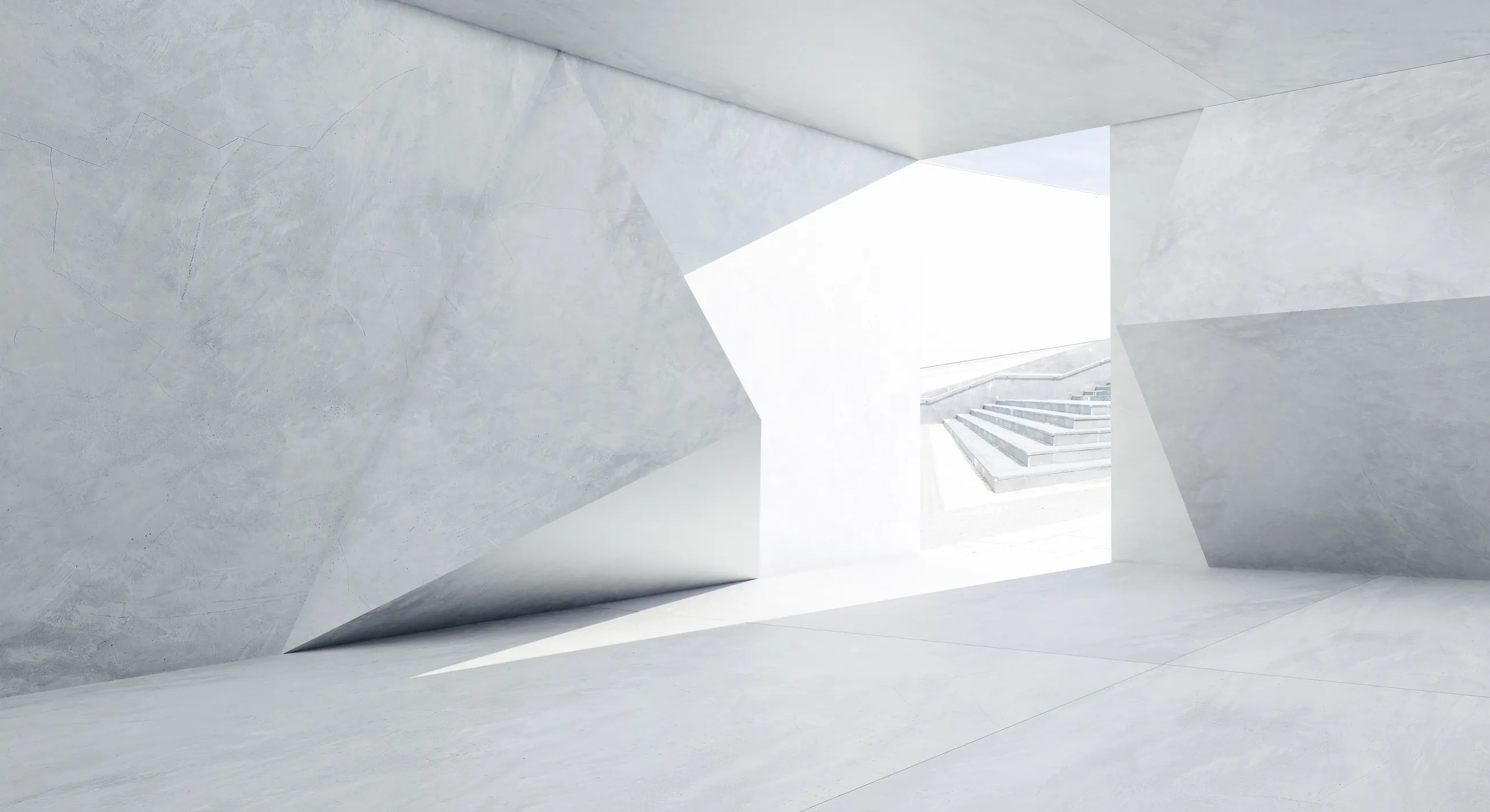 A pale faceted concrete passage opening onto daylight and a flight of steps.