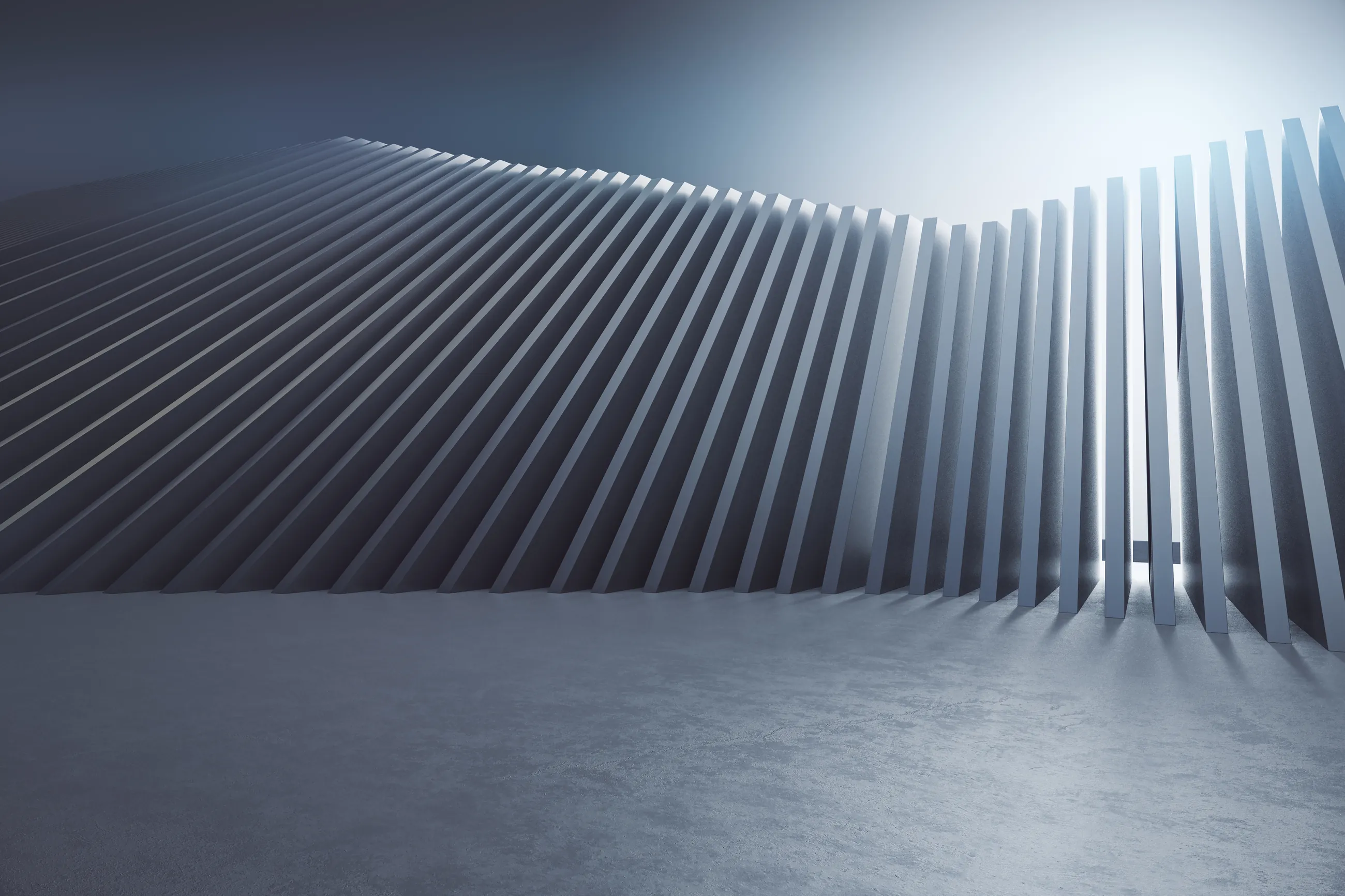 A long curved wall of closely spaced vertical fins, dark at one end and lit at the other.